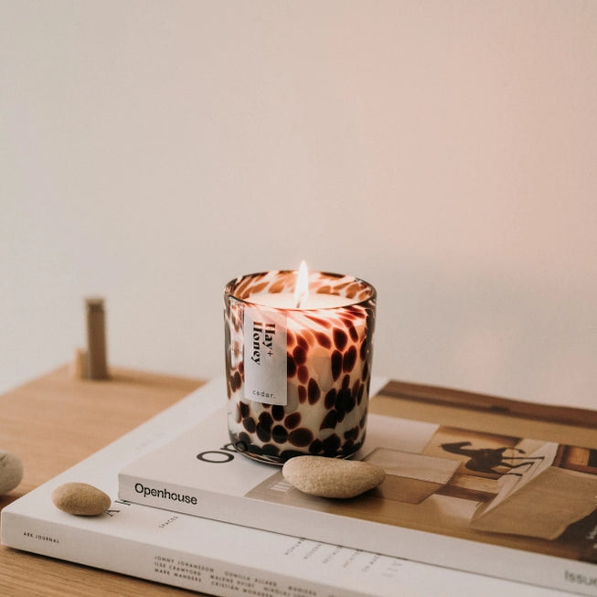 Cedar lifestyle hay and honey candle sitting atop two magazines