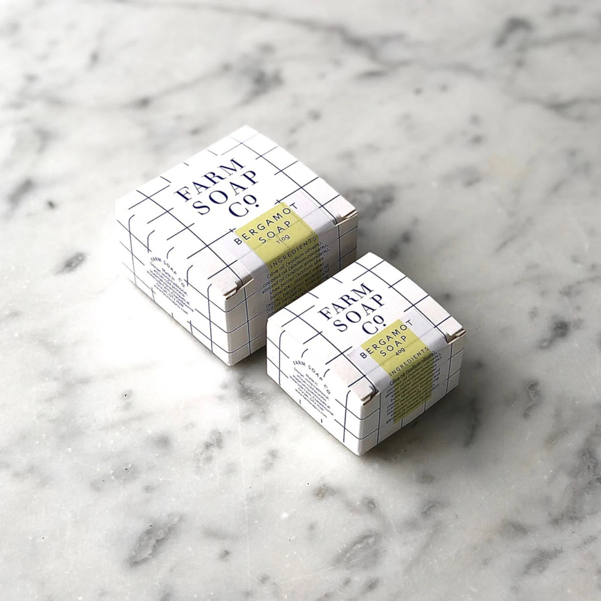 A marble background with 110g and 40g boxes of Bergamot Scented hair and body soap by Farm Soap Co