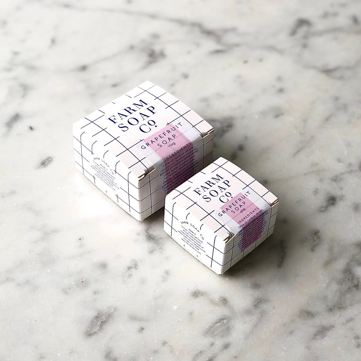 A marble background with 40g and 110g boxes of Grapefruit hair and body soap by Farm Soap Co