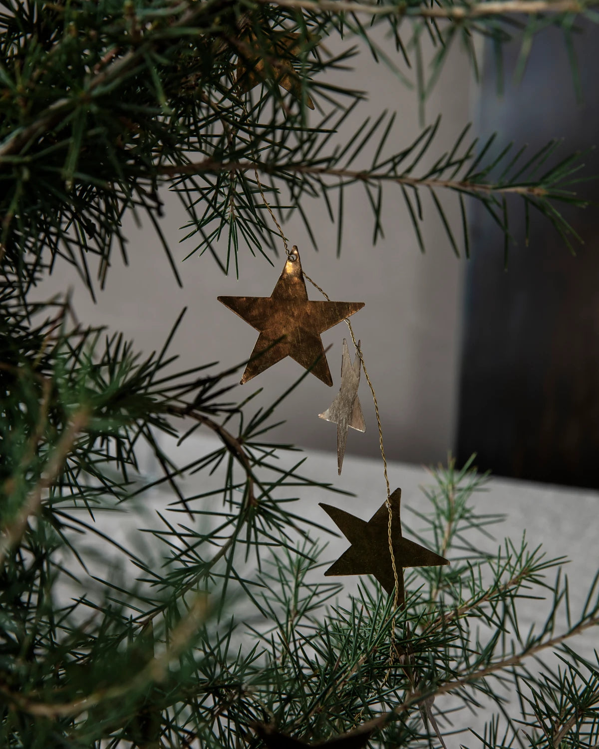 House Doctor antique brass star garland draped on a fir tree
