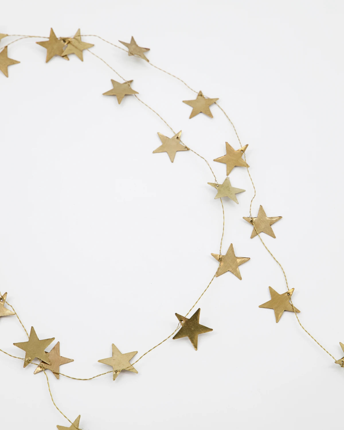 House Doctor antique brass star garland lying on a white brackground