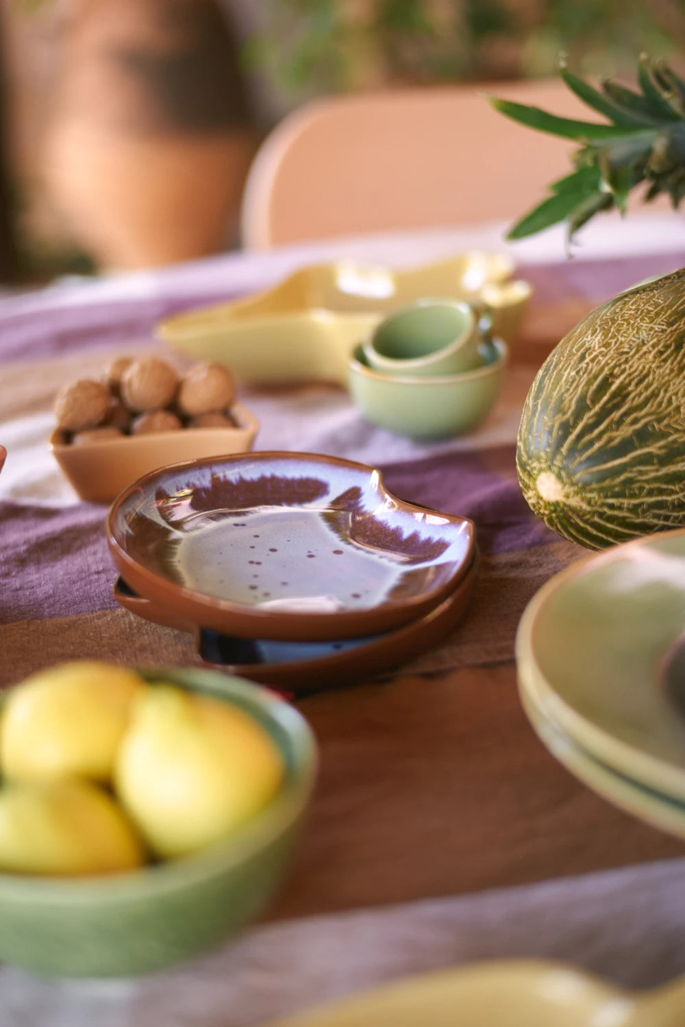 HKLIVING Ceramic Shell Plate in Sienna on a laid table with fruit and other pieces from the collection
