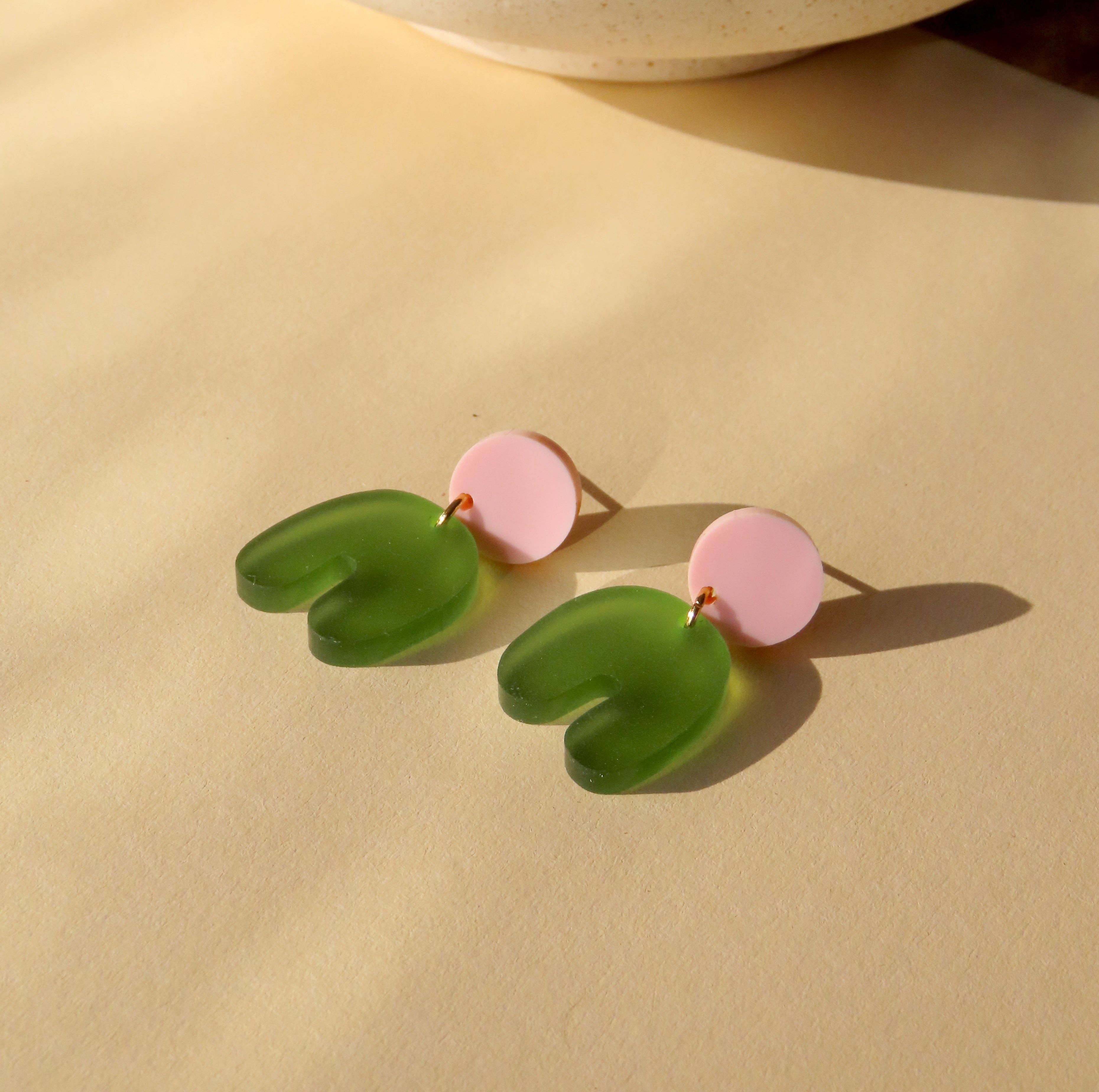 Niemalsmehrohne Squishy Arch Bow Earrings in Pink Olive on a  gold surface