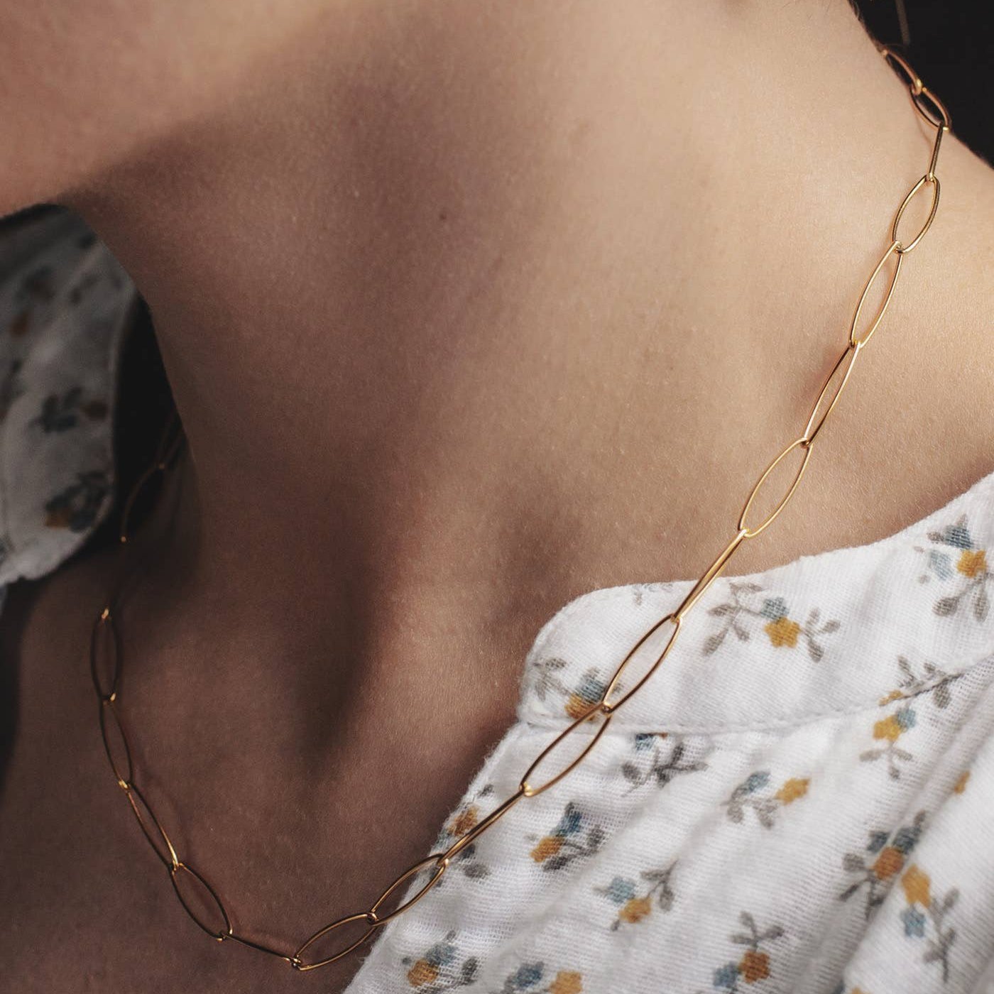 A close up view of the Gold Elongated chain necklace from Nordic Muse on a model