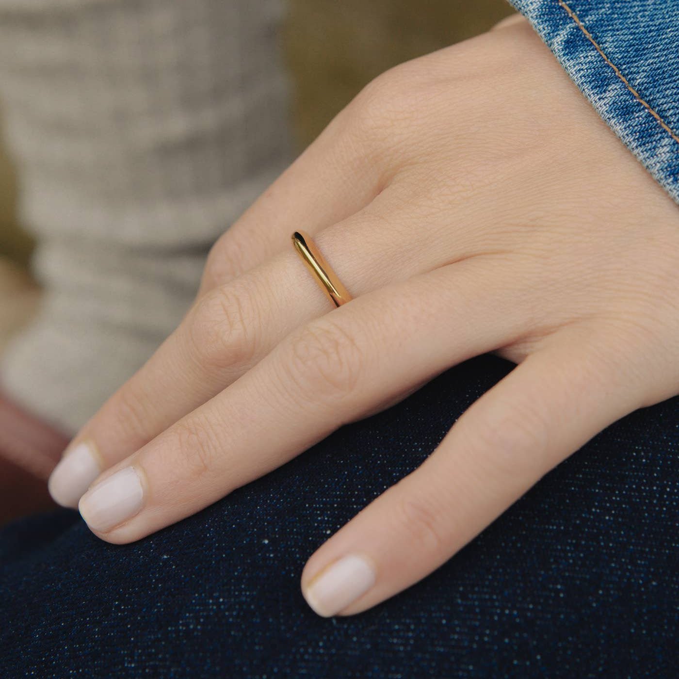 A close up view of a white persons hand wearing the gold irregular band ring from Nordic Muse on their finger