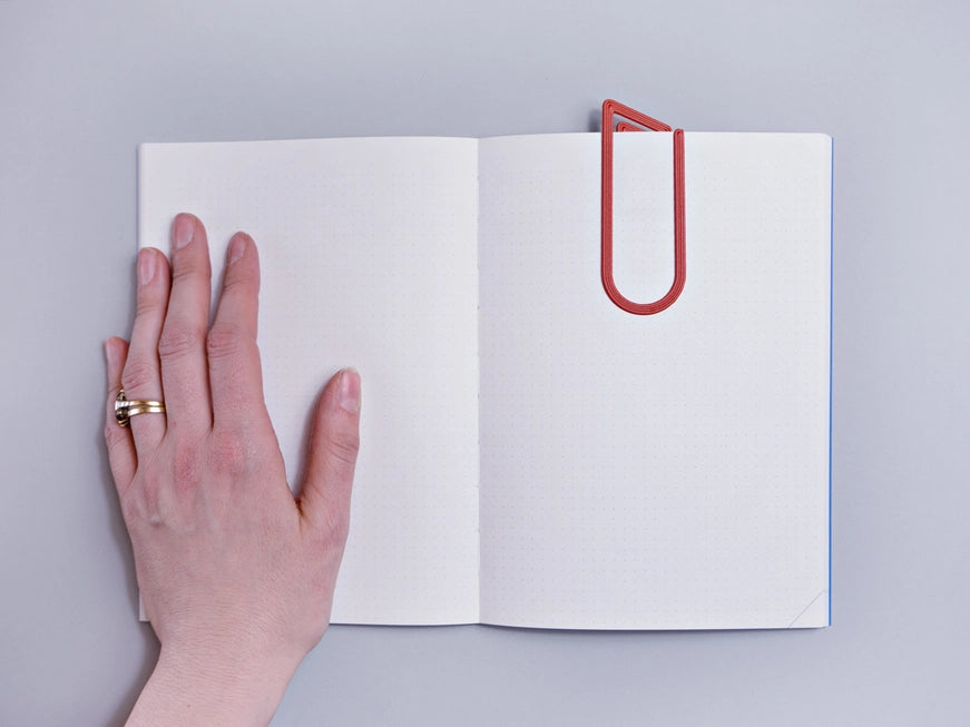 The Completist 3D Printed Modern Bookmark  slotted into a book with a human hand for size reference