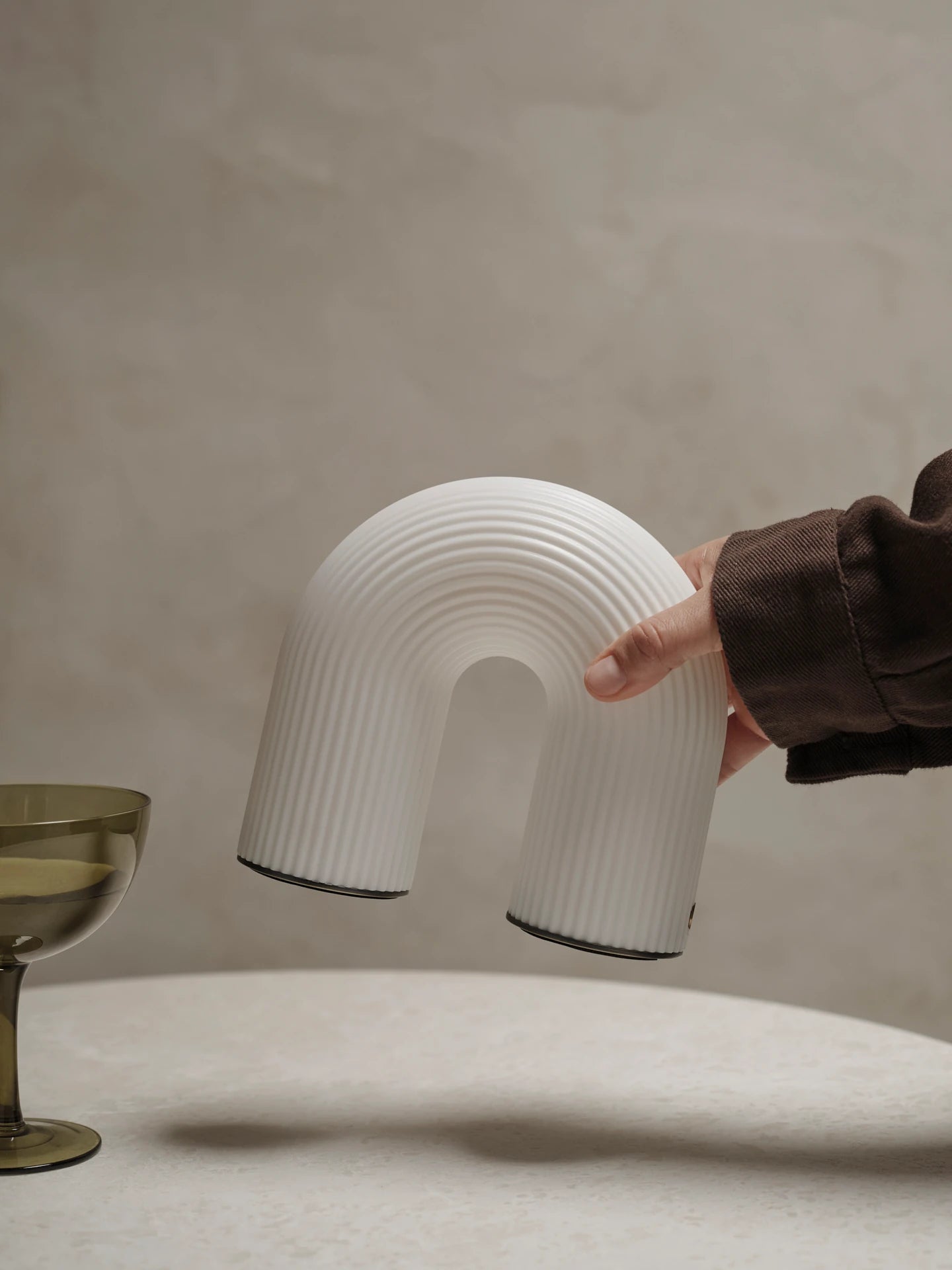 Vuelta Portable Lamp in White being placed on a table by ferm Living | Lifestory