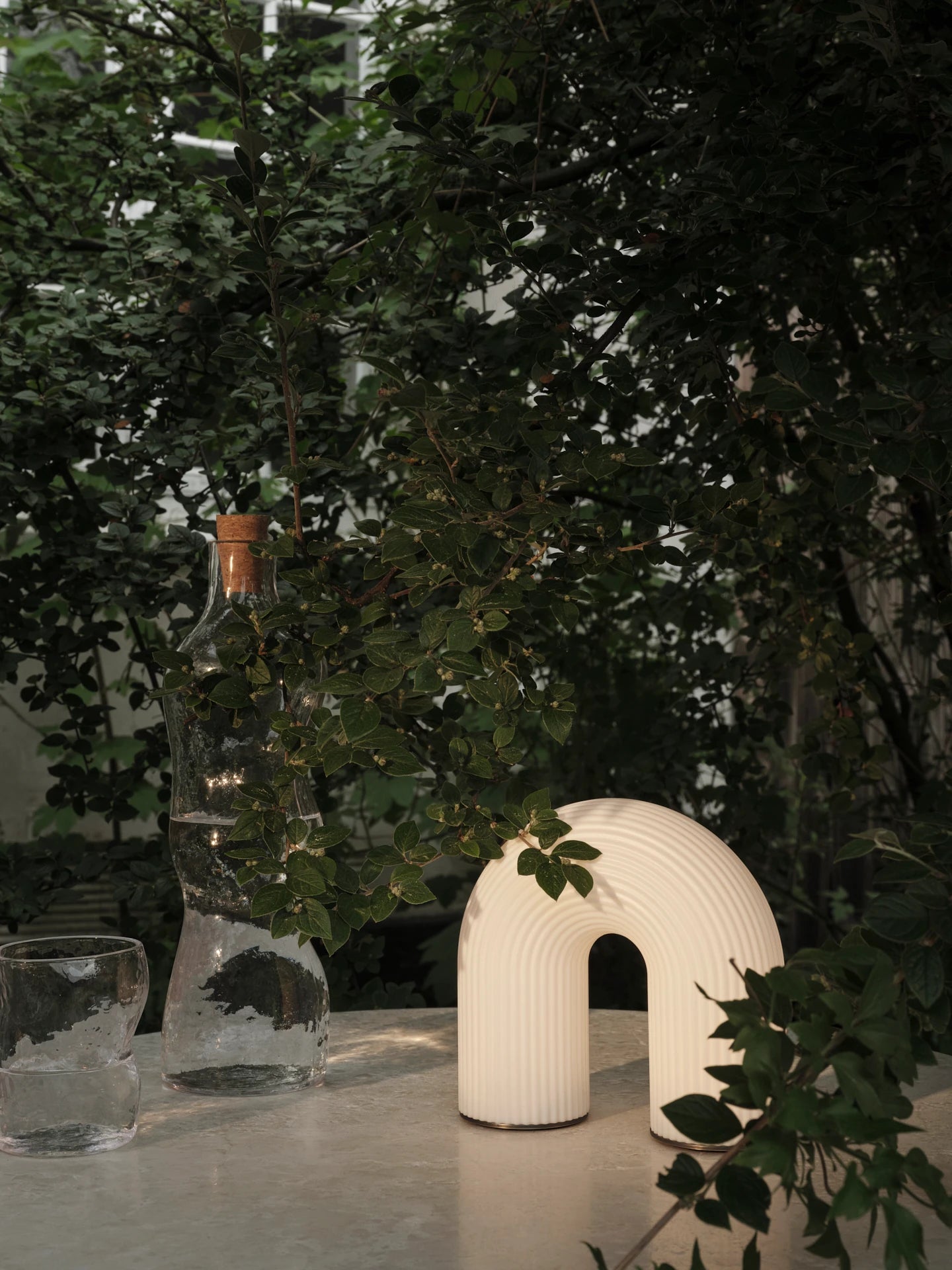 Vuelta Portable Lamp in White on an outside table by ferm Living | Lifestory